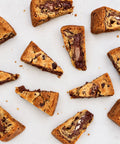 Several triangular chocolate chip cookie slices with melted chocolate filling are arranged on a light neutral background.