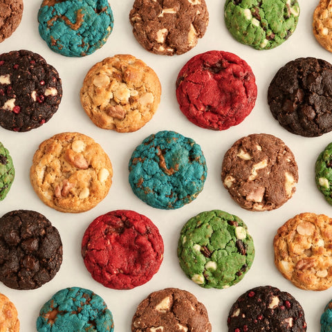 A top-down flat lay of colorful chocolate chip cookies arranged in a neat circular pattern on a light off-white background.