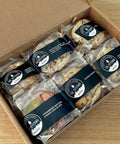 Box of assorted cookies with clear packaging and visible branding on a wooden surface