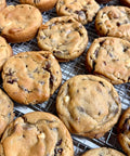 Close-up of several golden brown chocolate chip cookies cooling on a metal wire rack.