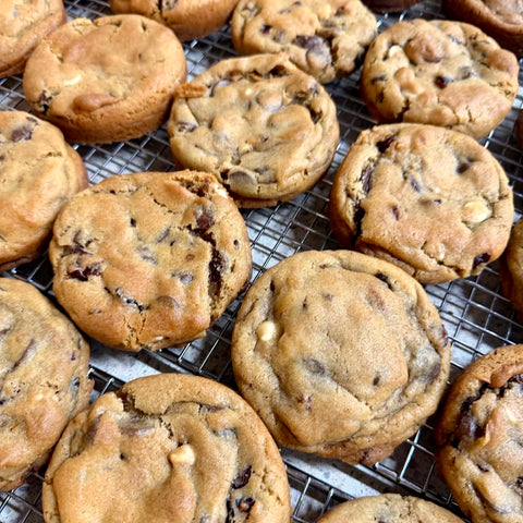 Close-up of several golden brown chocolate chip cookies cooling on a metal wire rack.
